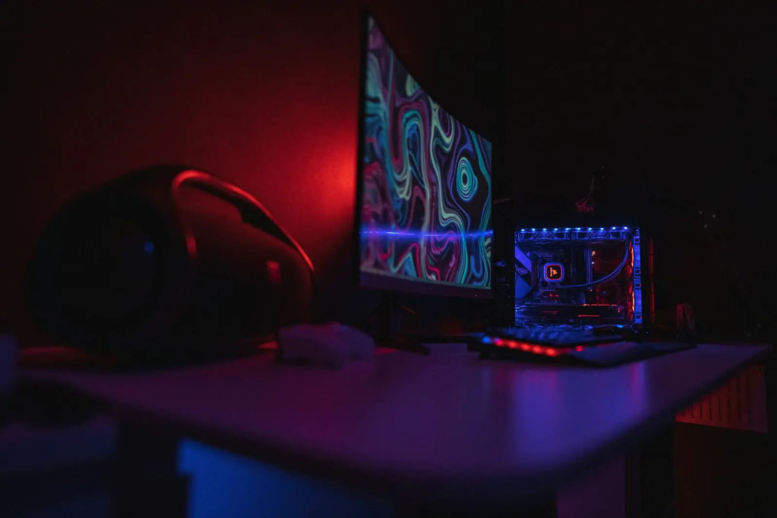 Kırmızı ve mavi RGB ışıklı karanlık oyun odasında kavisli monitör ve oyun bilgisayarı