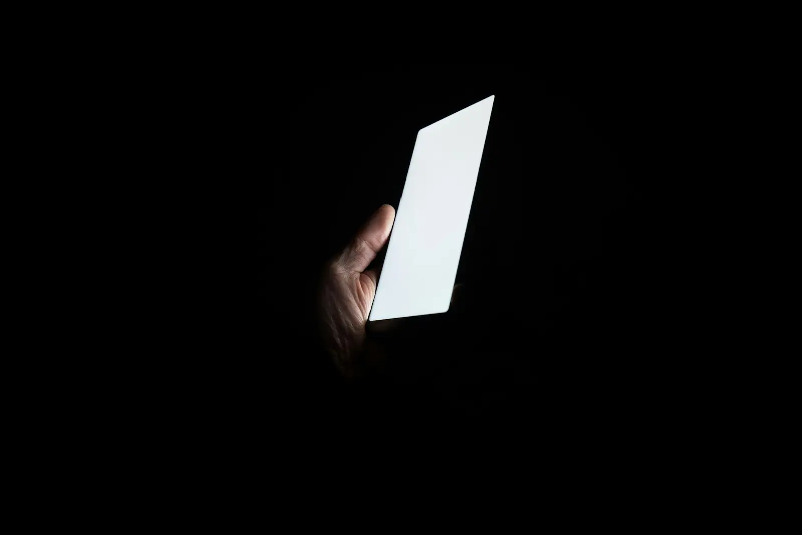 Zifiri karanlıkta ekranı parlayan akıllı telefonu tutan el