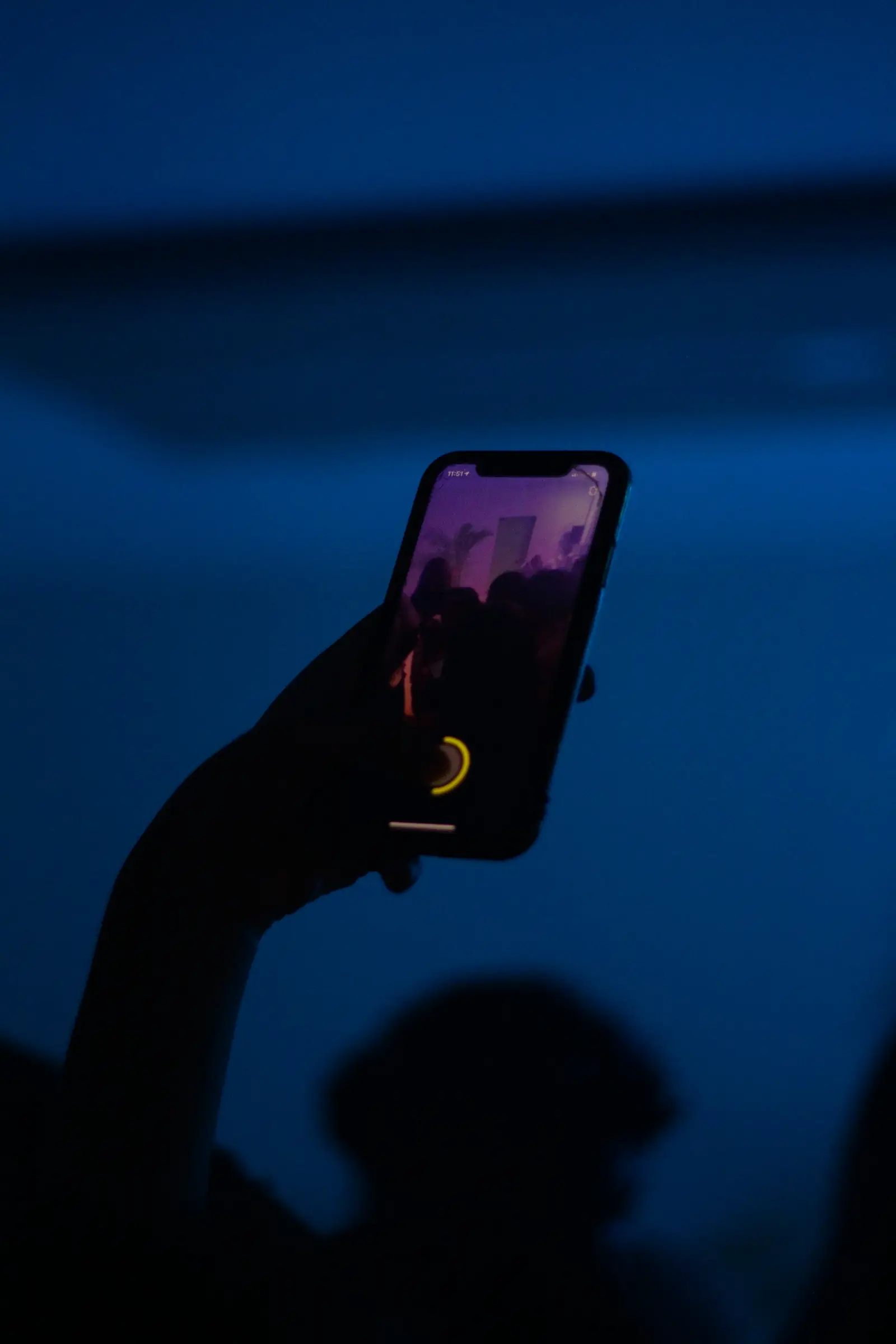 Mavi loş ortamda havaya kaldırılmış akıllı telefon